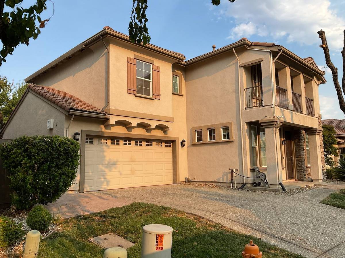 Before: tan two-story stucco home with brown shutters