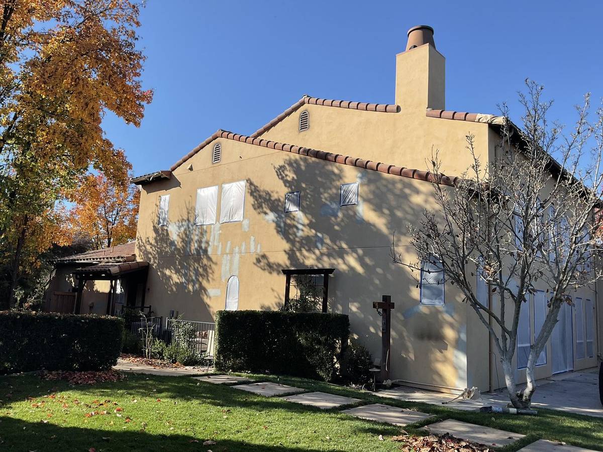 Before: yellow stucco home seen from the backyard